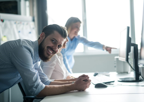 Businessman smiles by computers